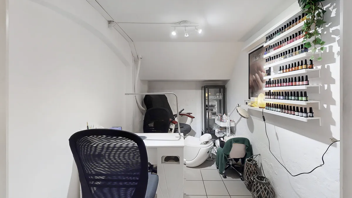 Et luksuriøst manikørsalon med hvid interiør og masser af opbevaringsrum til neglelak. Der er en barberstol og en masse