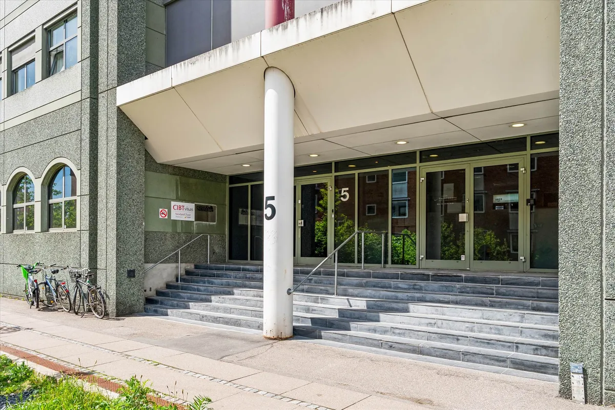 Træklave af trapper udenfor et bygning med grønne ruder og nummer 5. To cykler parkeret på siden af trappen