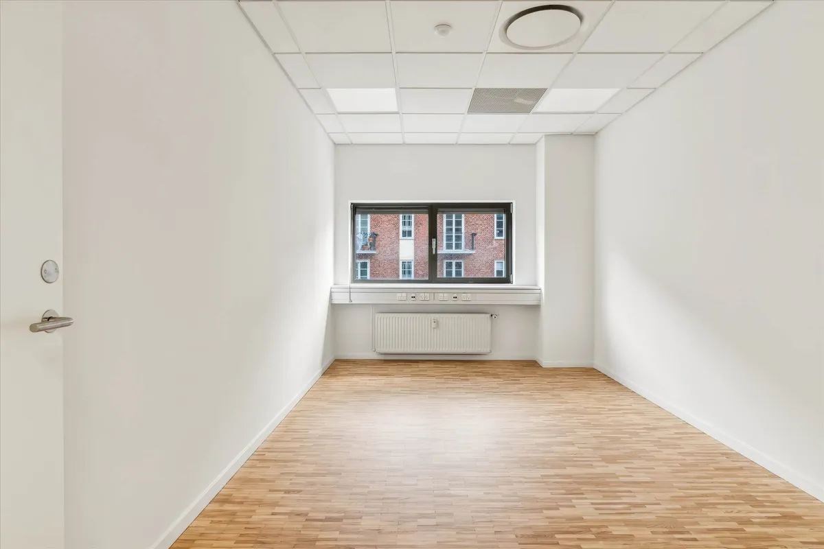 Moderne kontor med hvid væg og trægulv, højt loft med hvide loftbeklædninger og runde loftsventilatorer. Værelse med