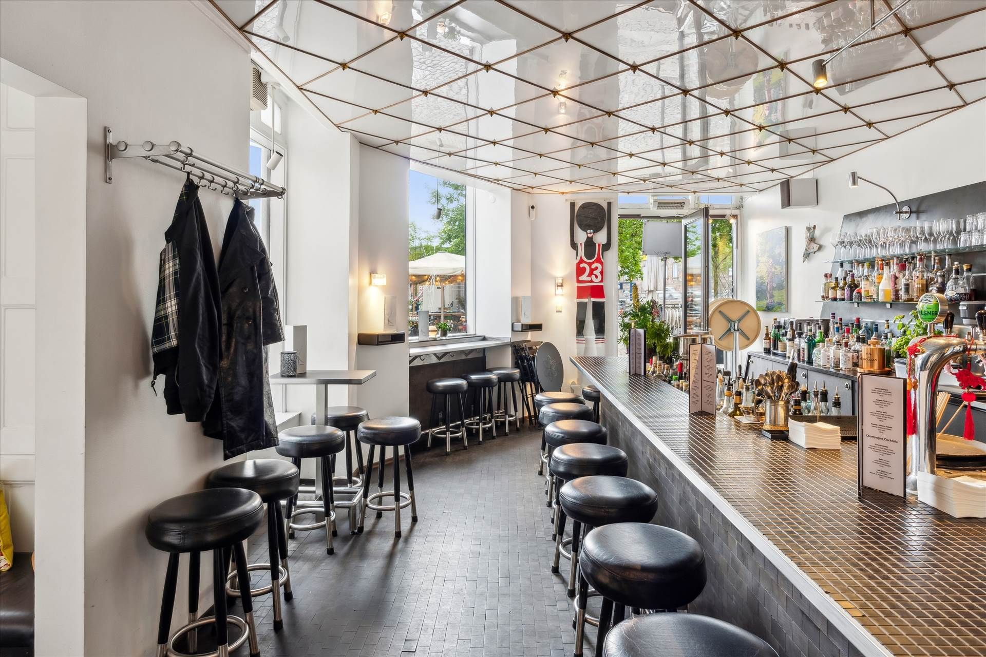 En elegant bar med krystaller og lysekroner, læderstole, en bardisk og en række alkoholiske drikke i glasskander