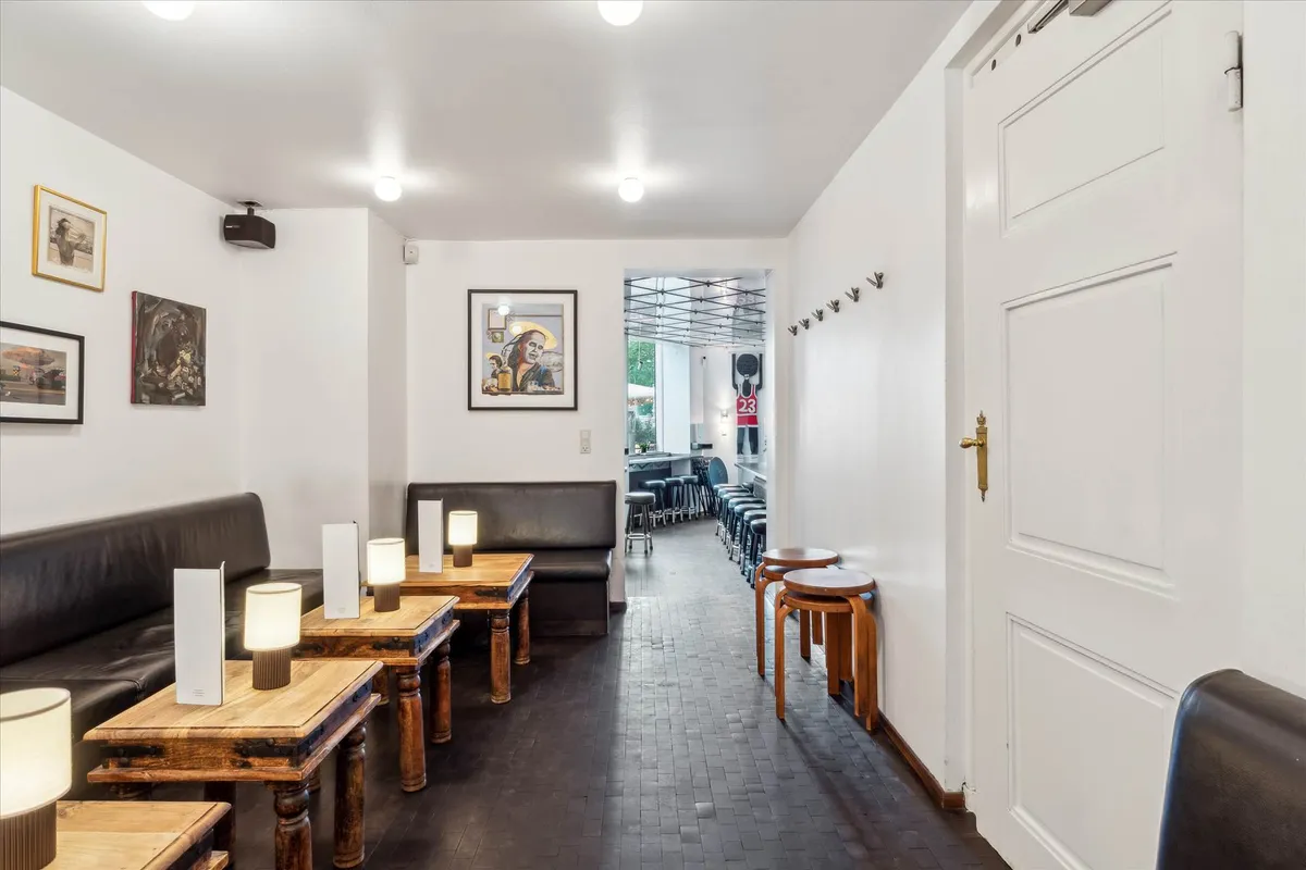 Indvendørs er der mørke lædersofaer, lyse træborde, lamper og kunstværker på væggen