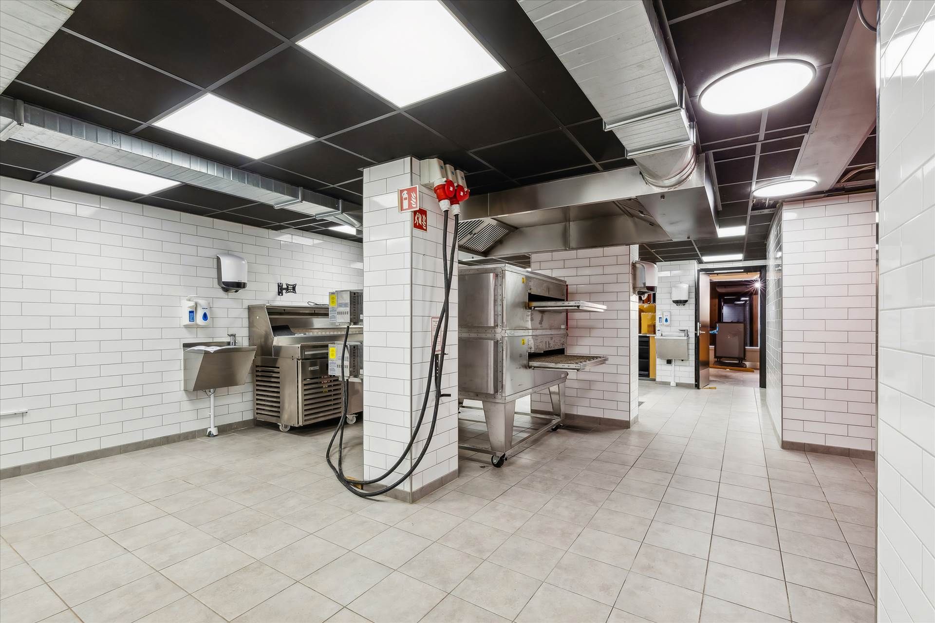 Moderne kommerciel køkken med flere apparater og en lysekron, der er installeret på loftet, samt flere hængekøkkener og