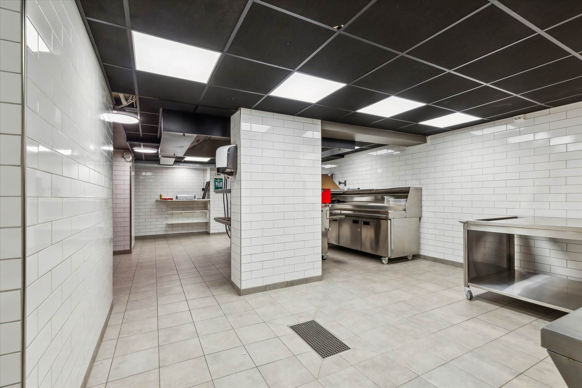 Rent og pænt kommercielt køkken med højt til loftet, lyse gulvfliser og hvide kakelvægge