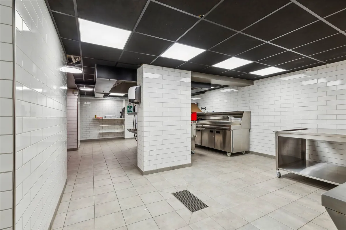 Rent og pænt kommercielt køkken med højt til loftet, lyse gulvfliser og hvide kakelvægge