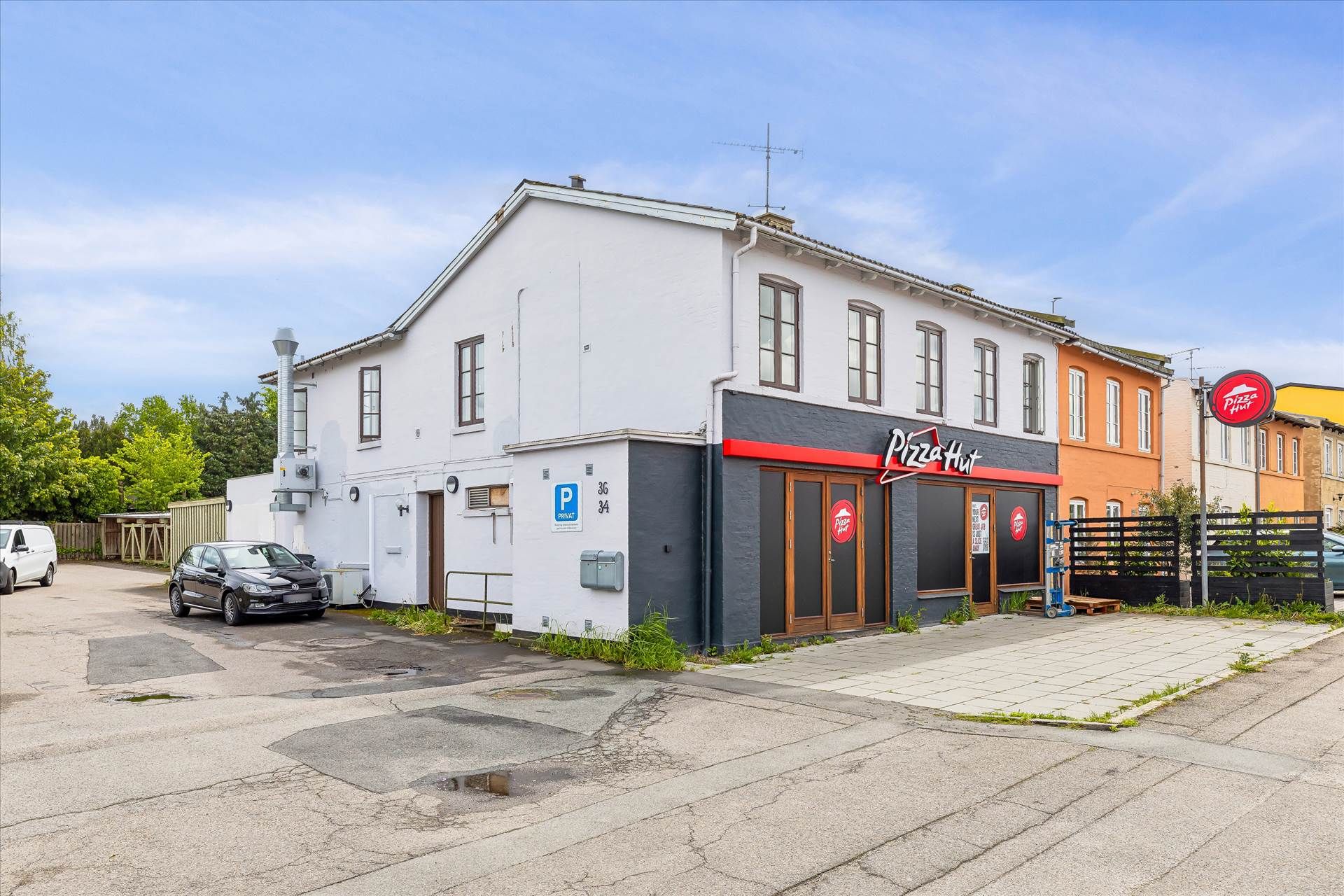 Pizza Hut-restaurant med parkeringsplads foran og et køretøj parkeret på området