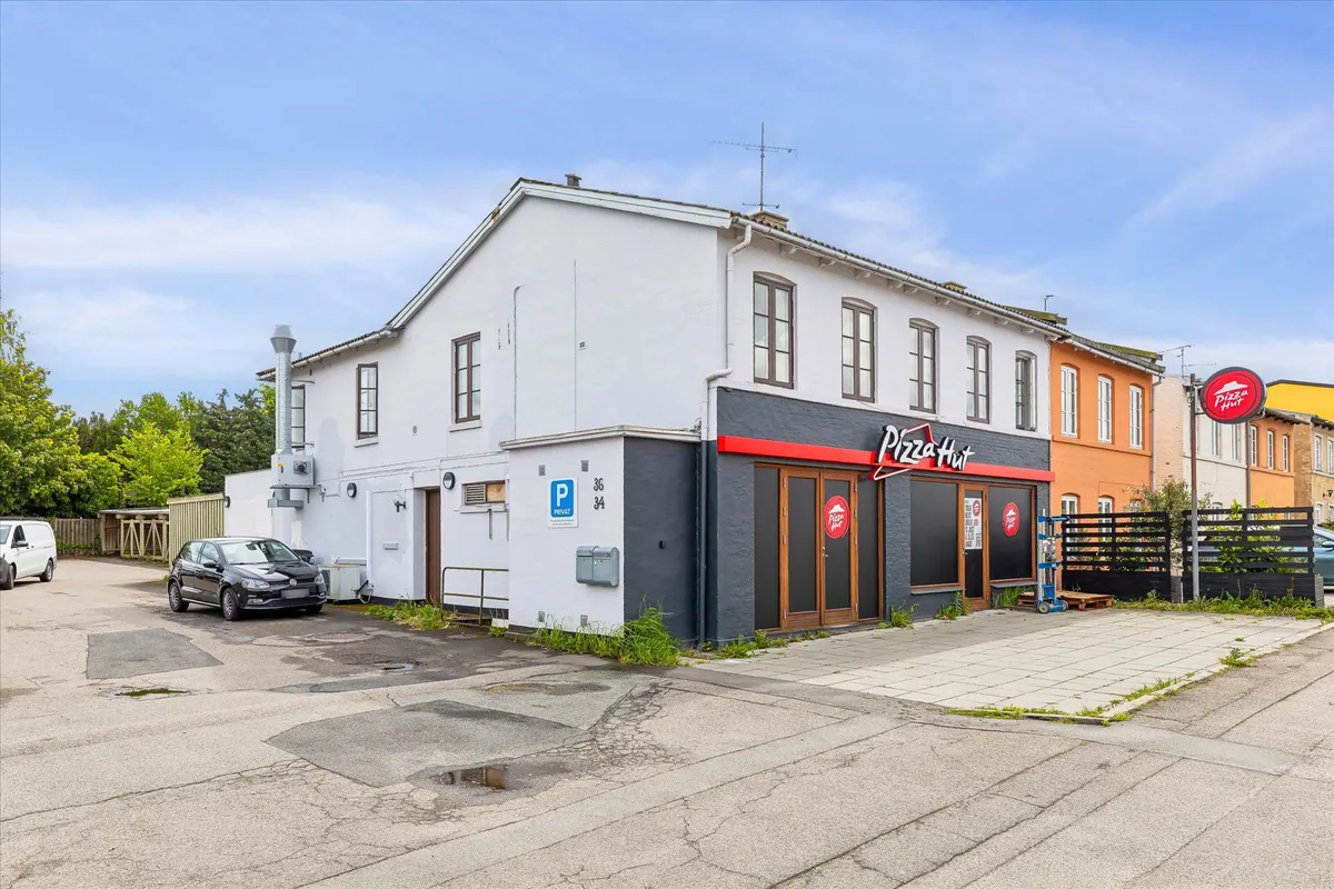 Pizza Hut-restaurant med parkeringsplads foran og et køretøj parkeret på området