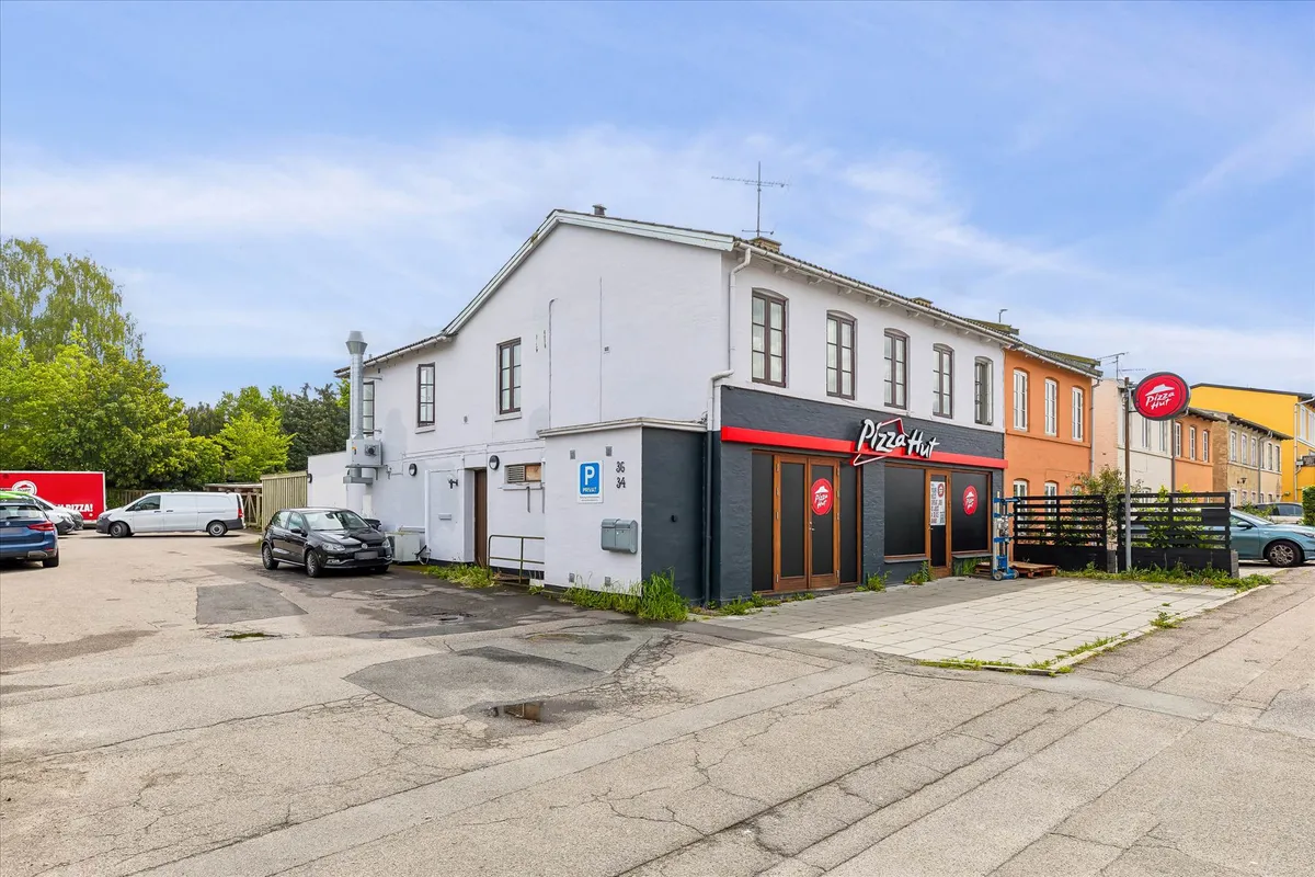 Pizza Hut restaurant med parkeringsplads foran og andre forretninger på gaden