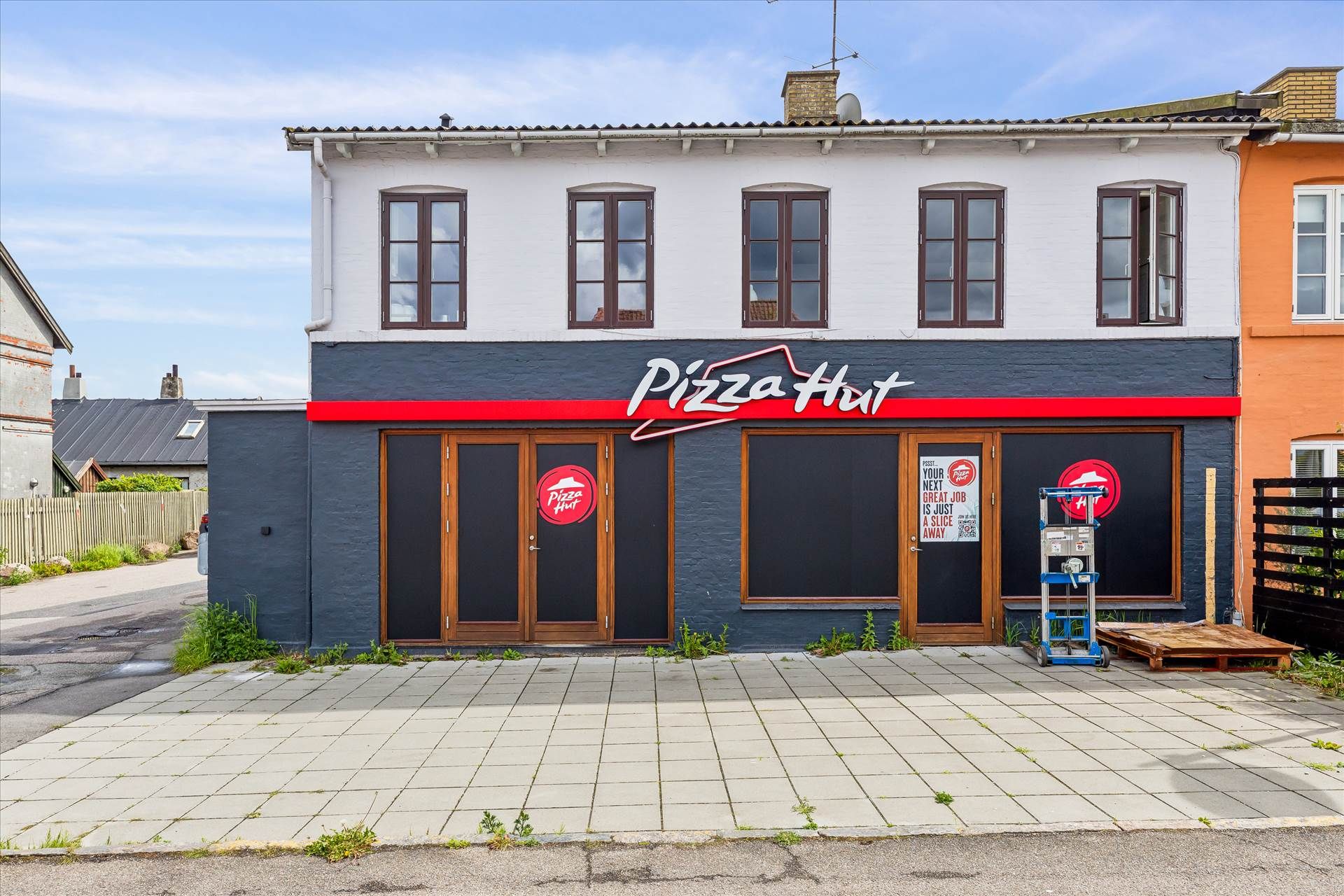 Pizza Hut restaurant med lukket dør og skilt med teksten Pizza Hut i hvidt og rødt