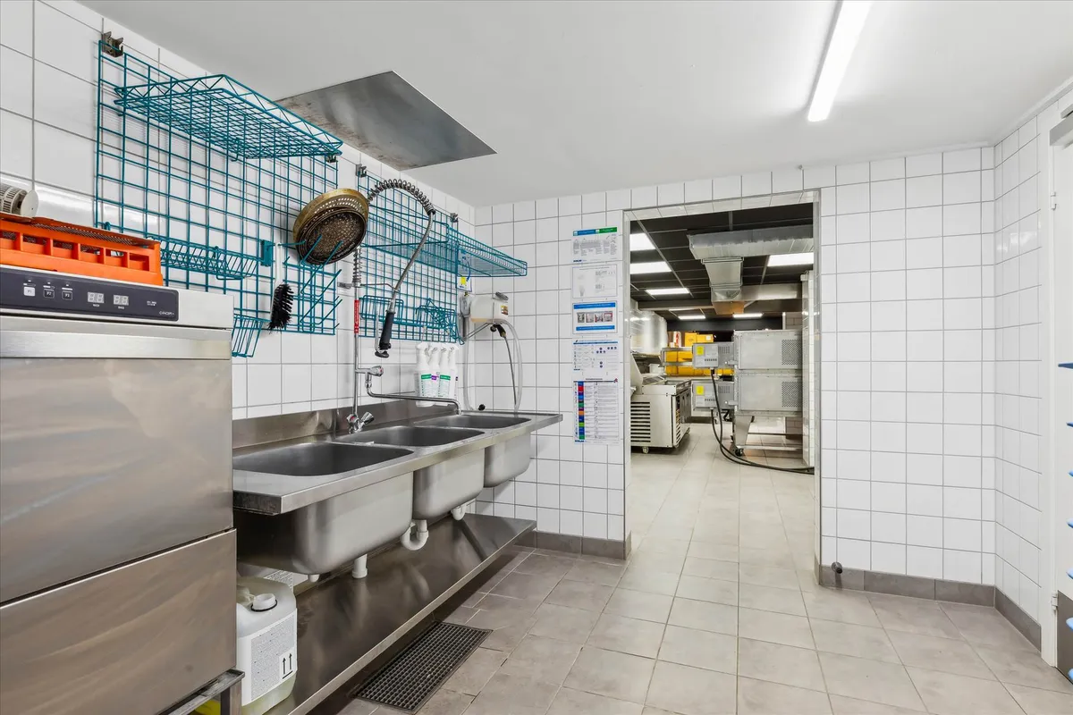 Renseri med to stålvaske og renseriprodukter, samt renseriværktøj og opbevaringshylder. Adgang til køkken med udstyr og