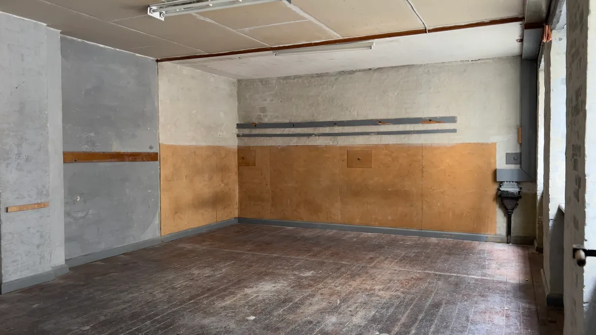 Et værelse med tømmervægge og gulv, skrald på gulvet og udvendige vægge med revner og hulrum