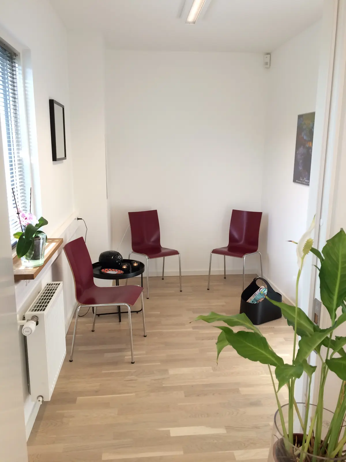 Lejlighed med 22 m2. På loftet er der 2 røde stole, et bord og en blomst i et glas. Der er også en radiator og et kunstværk