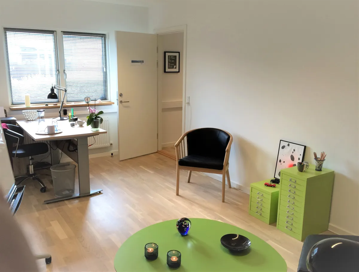 Lejlighed med møbleret kontorlokal og gulvbelægning, træbord, to stole, to skraldespande og en grøn rund bord