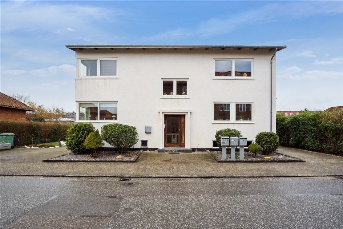 Alt om hus i Fredericia med terrasse, lysevinduer og parkeringsplads. Hvidt hus med tre etager og sollys, der skinner gennem