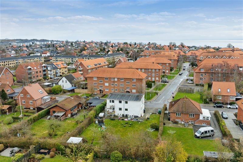 Frederikshavnsvej i Fredericia med boligblokke, grønne områder, parkerede biler og en gågade