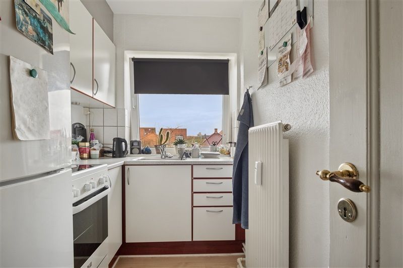 En veludstyret køkken med lyse lofter, hvide skabe og en stor køleskab i hvidt