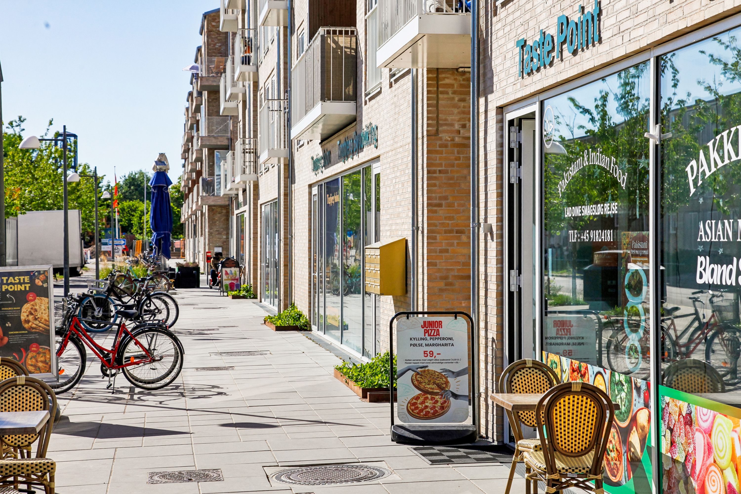 en gågade med restauranten Taste Point og en række cykler og stole parkeret på siden af gaden