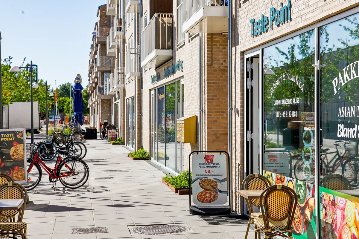 en gågade med restauranten Taste Point og en række cykler og stole parkeret på siden af gaden