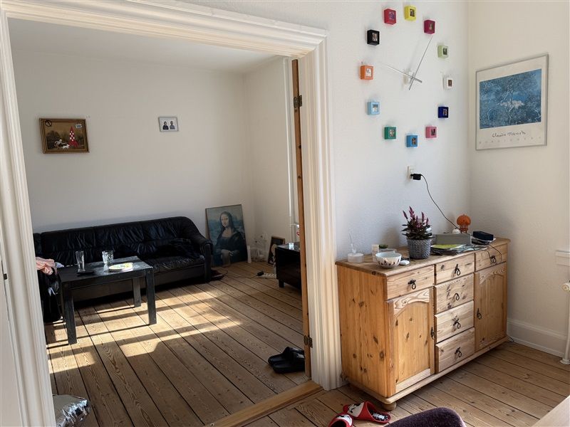 Soveværelse med møbler og indretning i moderne stil, sofa med glasbord, gulvtæppe og kunstværker på væggen