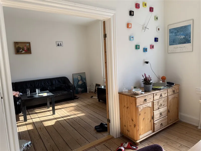 Soveværelse med møbler og indretning i moderne stil, sofa med glasbord, gulvtæppe og kunstværker på væggen