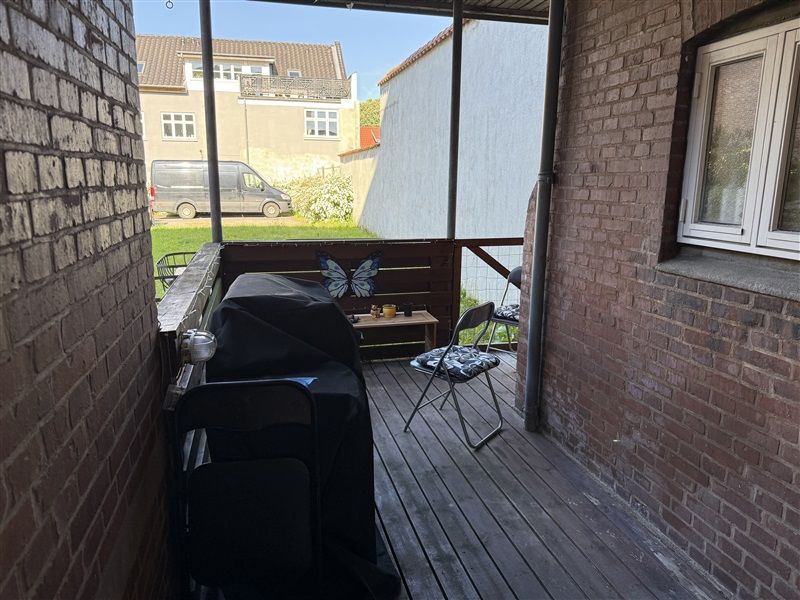 Balkon med grill og stole og bord med kuglepenne og krydderier i et hjørne