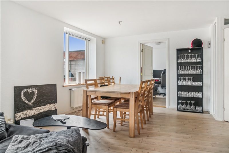 Her er et foto med et moderne interiør med et træbord og stole samt et skab med vinglas og et kærlighedsmotiv