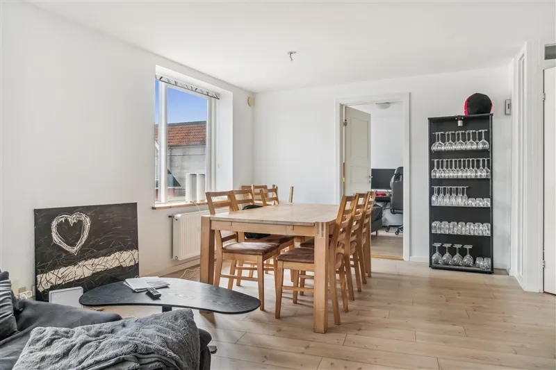 Her er et foto med et moderne interiør med et træbord og stole samt et skab med vinglas og et kærlighedsmotiv