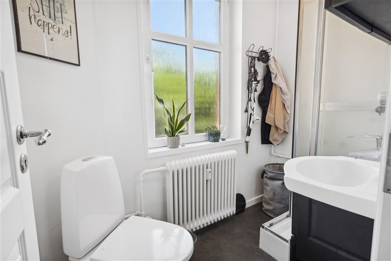 På dette badeværelse er der et toilet, et badekar, en radiator og en hvid skraldspande.