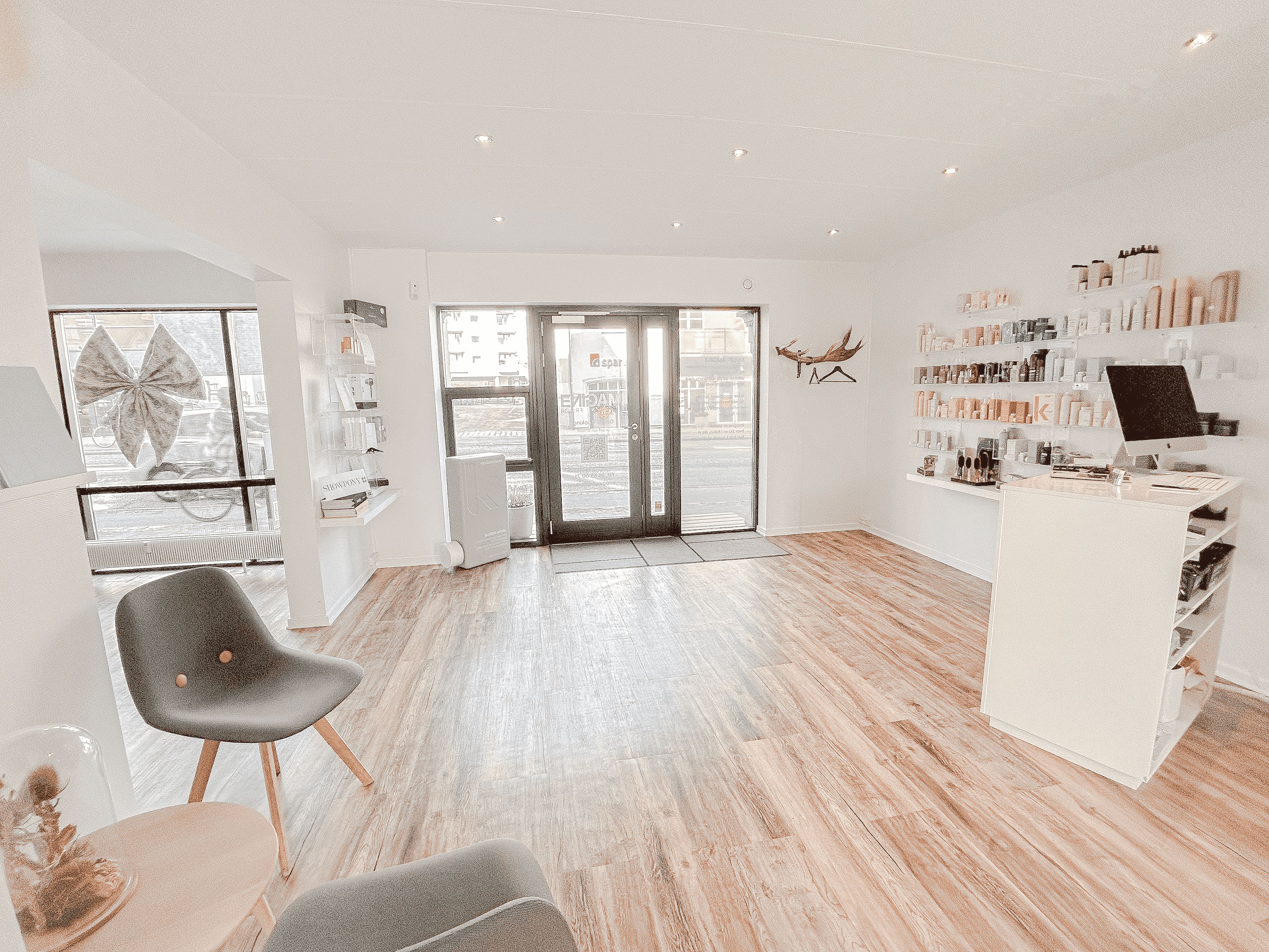 Det lyse, velholdte interiør med højt til loftet, trægulv og møbler samt eksklusive produkter placeret på hylder og disk