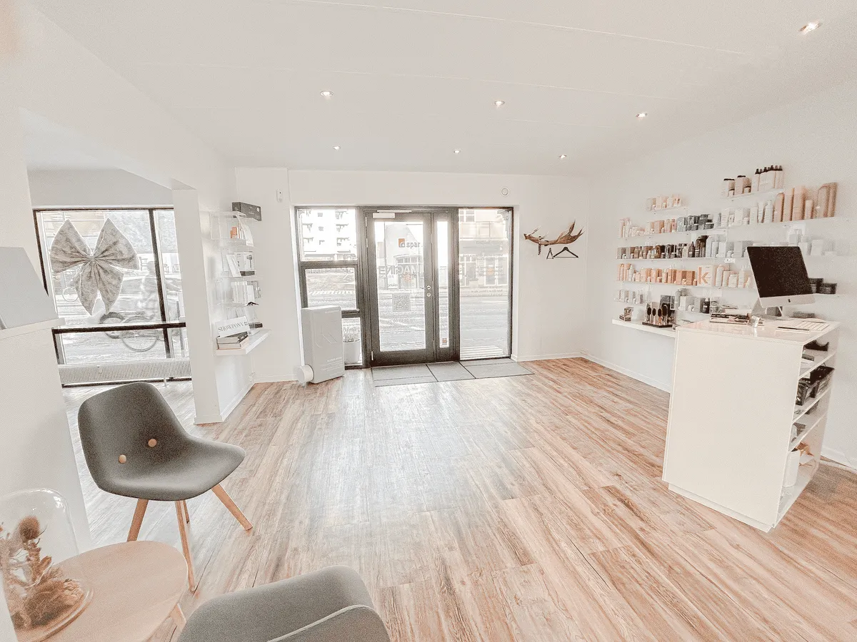 Det lyse, velholdte interiør med højt til loftet, trægulv og møbler samt eksklusive produkter placeret på hylder og disk