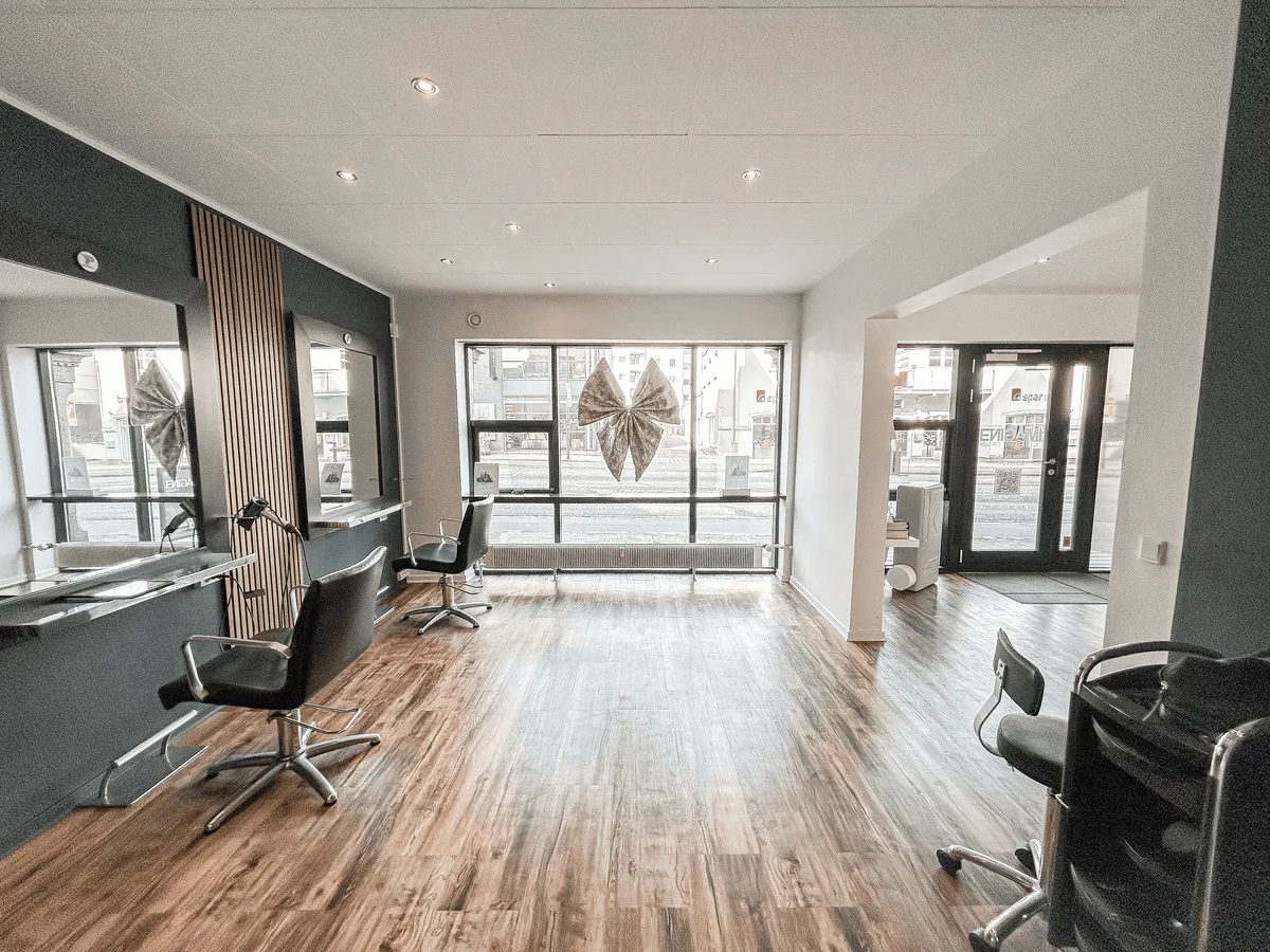 Salon med stolpedesign og høje lofter, glasdøre, hårstylingstolpe, vinduesdekoration og højteknologisk udstyr i et velholdt