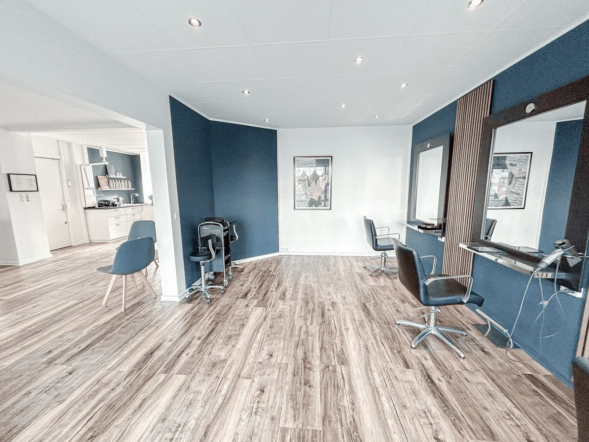 Nydelig frisørsalon med moderne møbler og lyse farver, blå vægge og hårklippestativer med sæder og spejle