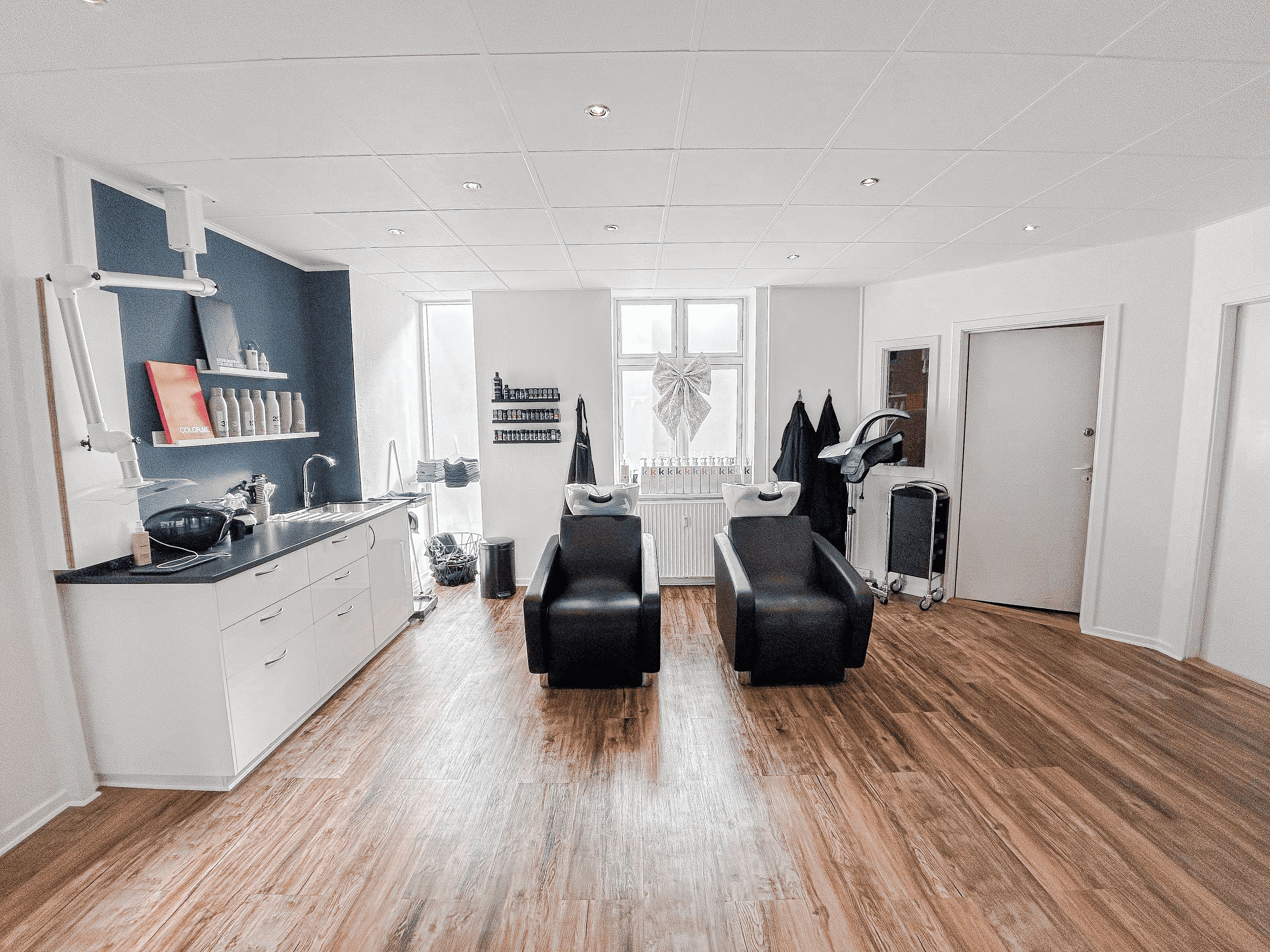 Indvendigt billede af en velplejet frisørsalon med to moderne hårstylingstole, ren, lys og luftig indretning med lysegult