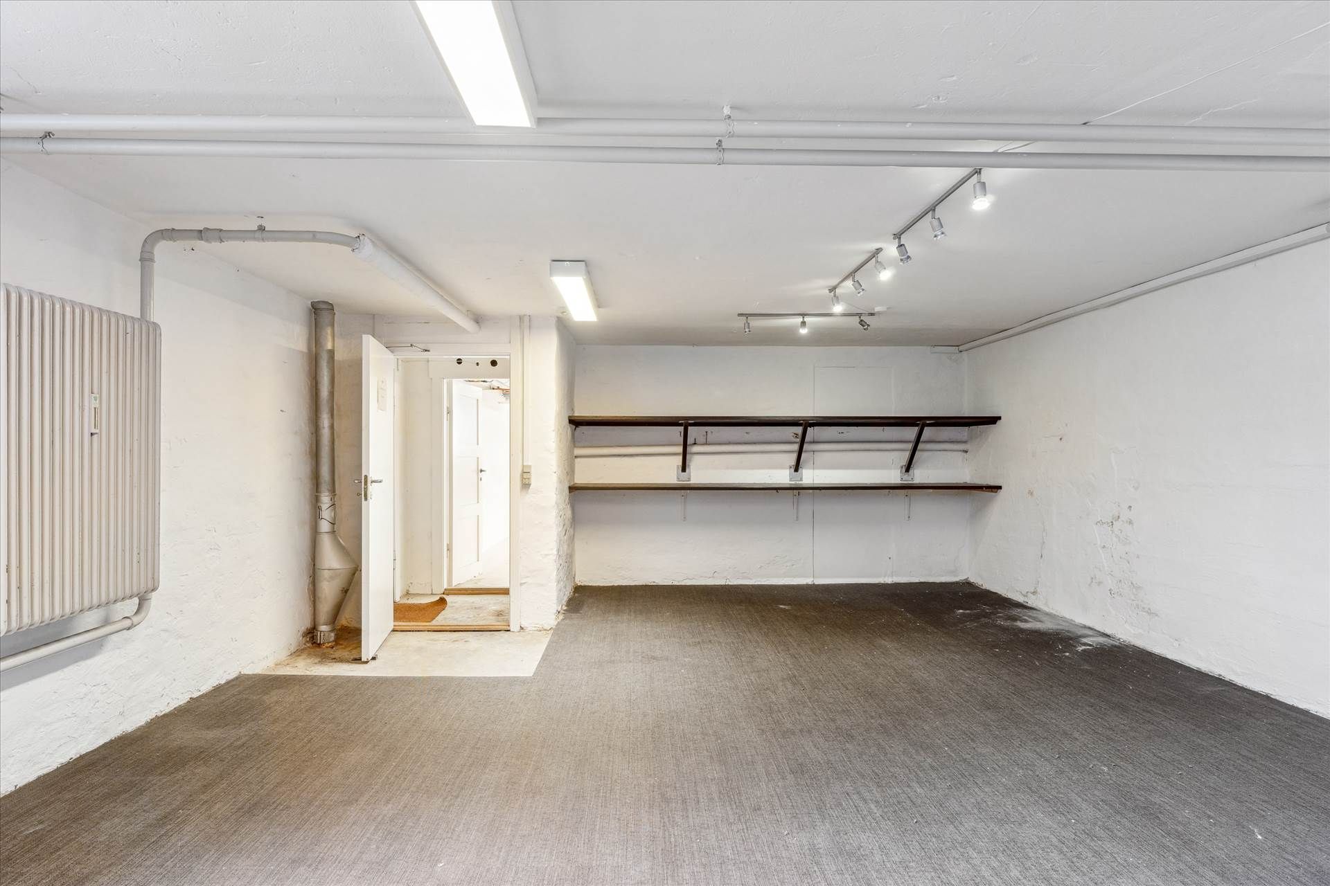 Lejlighed med to åbne døre og to hylder samt radiator og røgaffugter i gulvet