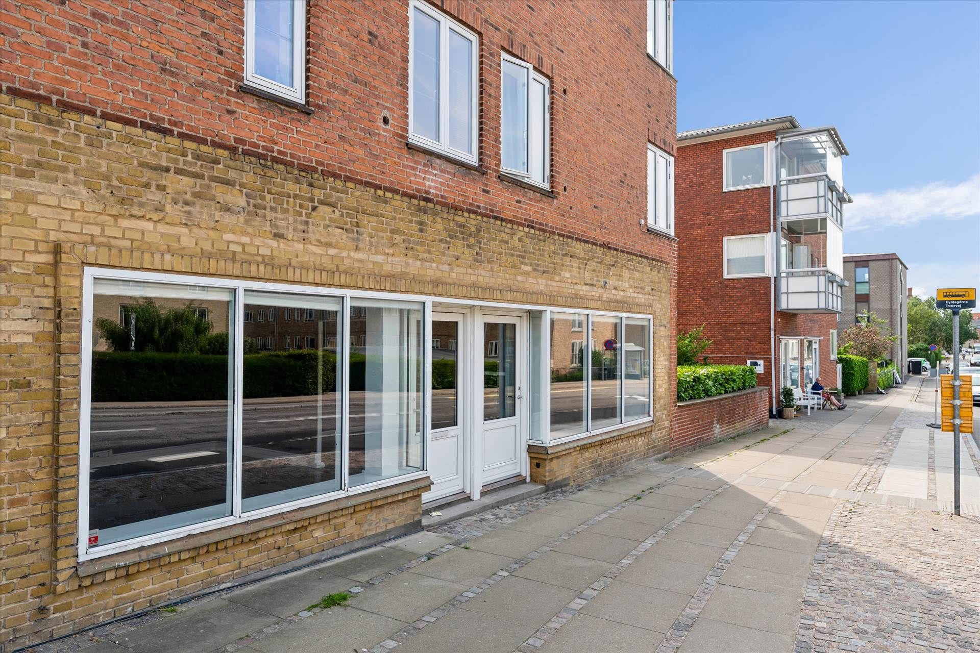 En stor rødmalet lejlighed med store glasruder og en hvid indgangsdør i centrum af en by