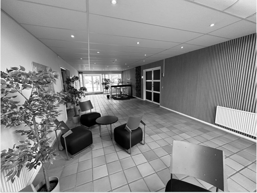 God lobby med lyse cellekontorer, plantager og stolpe med trægulv