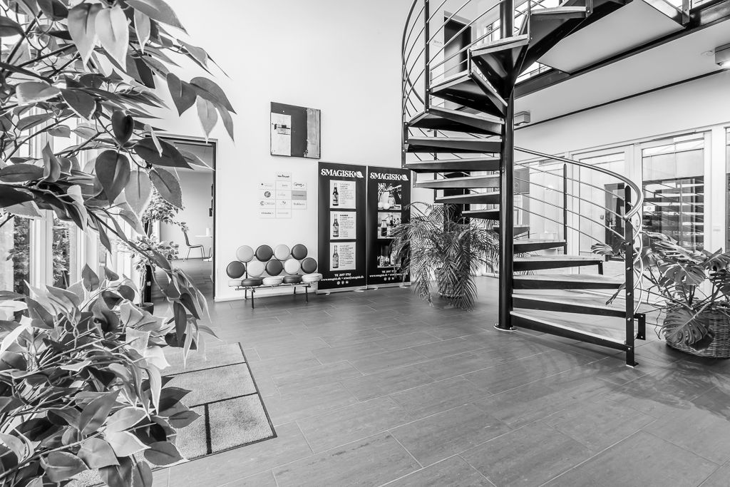 Kontorhotellet har glasdøre og en indgang med trægulve og møbler, samt store planter og skråtrappe