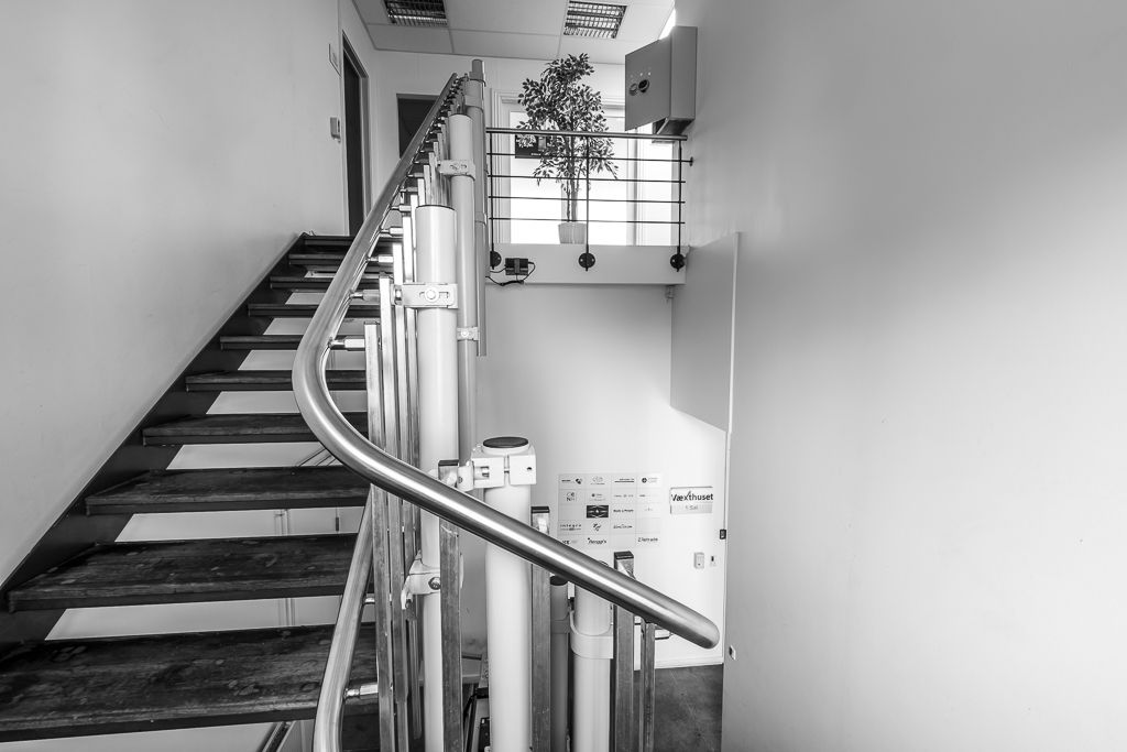 Kontorhotel med indvendig trappe og håndtag, der fører til en terrasse med plante og metalrammer