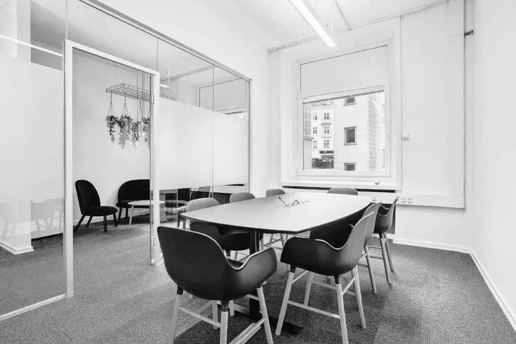 En moderne kontorværelse med ovalt bord og flere stolpe og plantehængere med små plantager