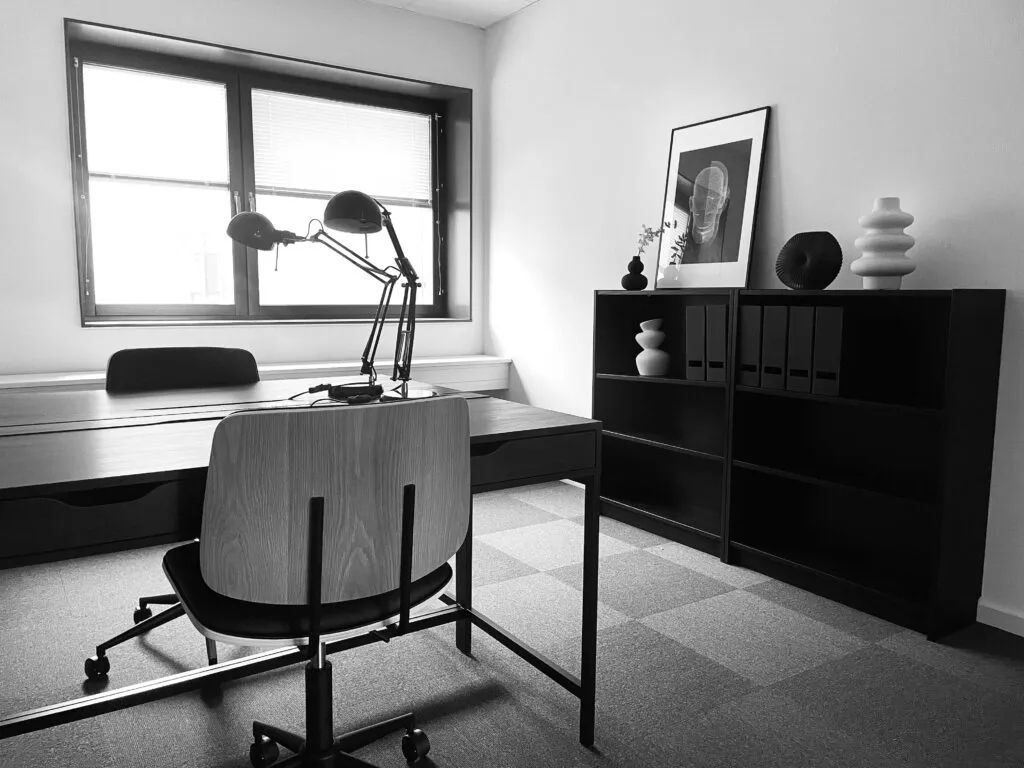 Kontor med skrivebord, stol, lampe, kabinet, billede og andre genstande