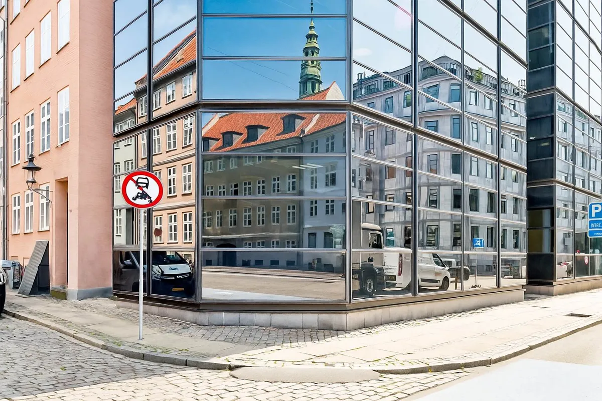 Kontorbygning med spejleglas og rødt tag, sammen med en søjle og gamle bygninger i baggrunden