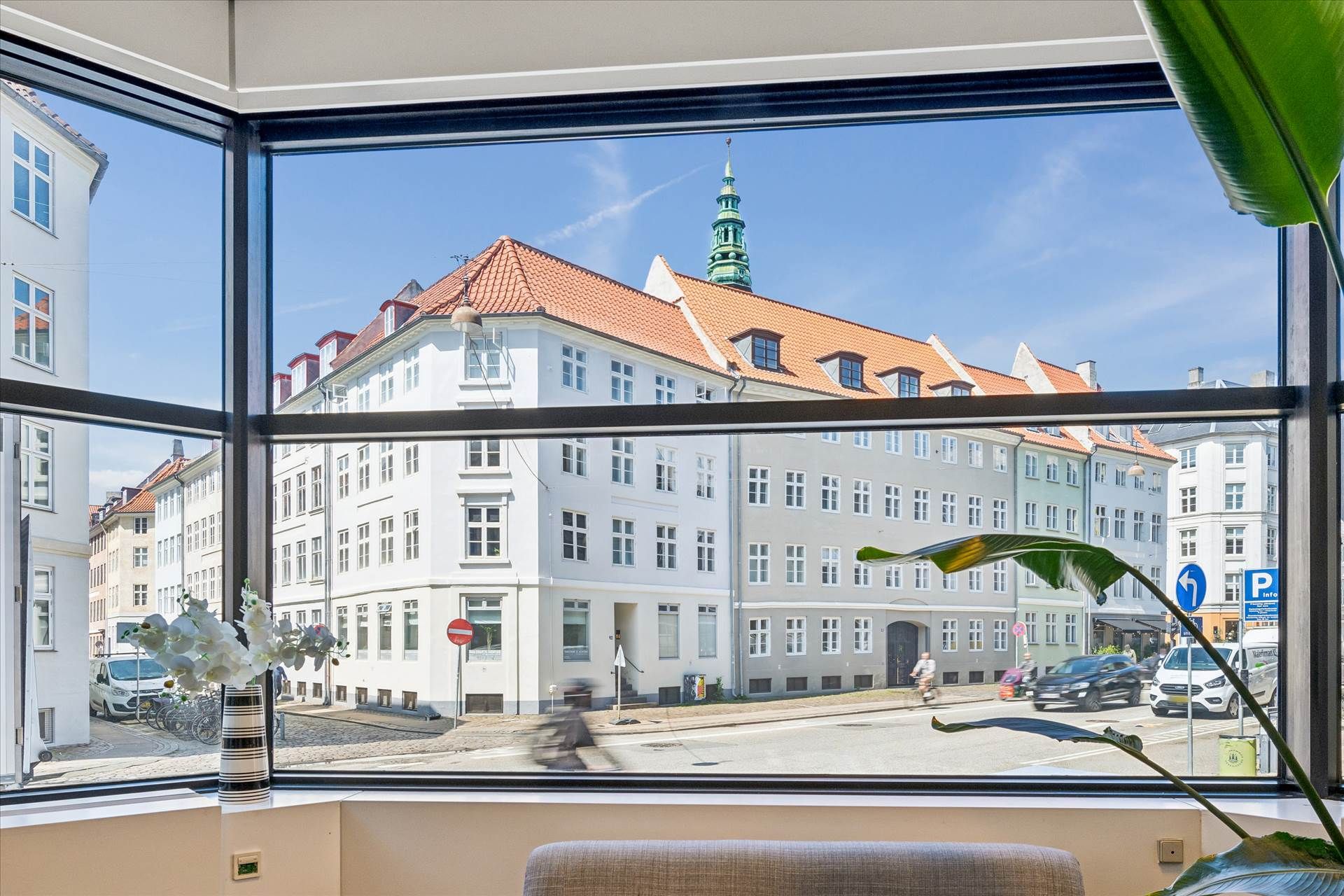 Kontor i København med udsigt til gade med biler og cyklister og blomster i en vase