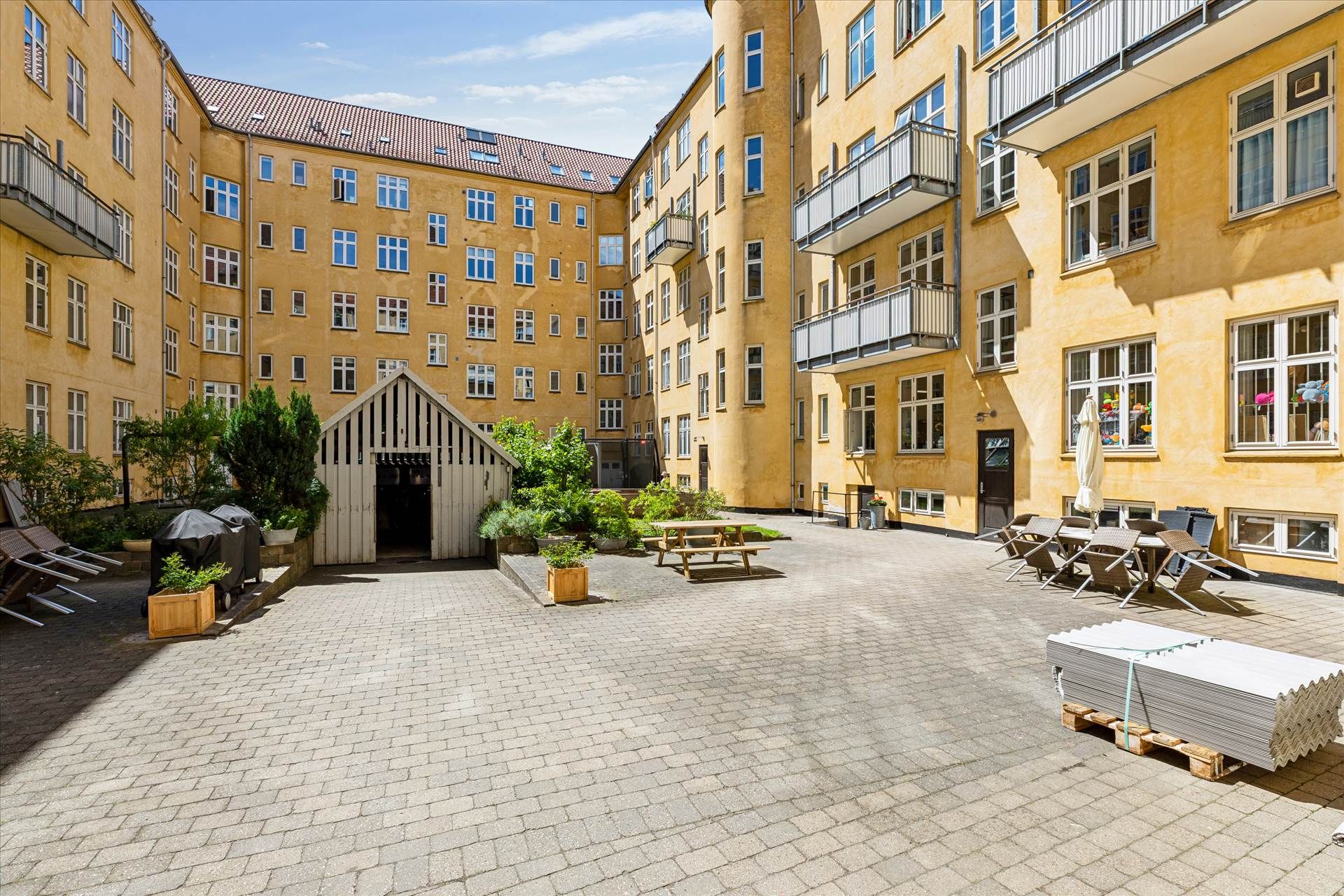 Et eksklusivt lejlighedskompleks med terrasser og parkeringsplads foran en bygning med terrasser og vinduer