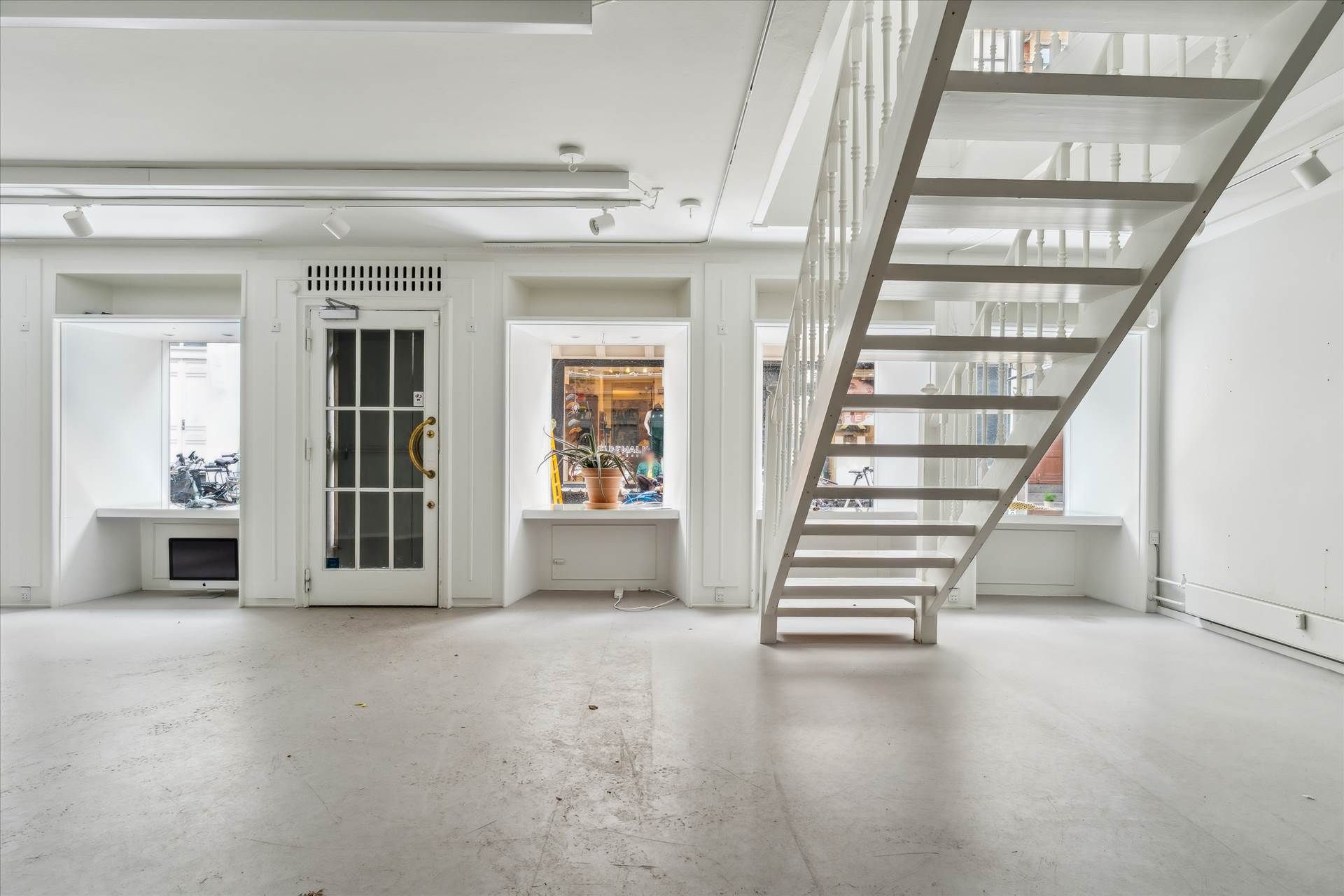 Indenfor et rummeligt og lyset lokale er der et hvidt køkken med lyse trægulve og en stor vinduesudsigt