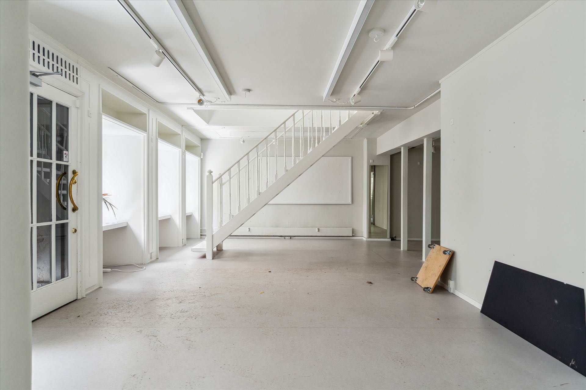 Et lyst, rent og luksuriøst rum med hvide vægge og gulv samt hvide loftslamper og hvide trapper til øverste etage