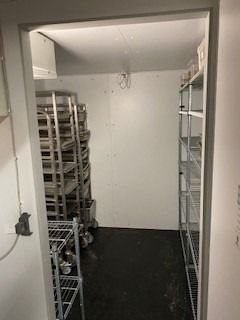 Værelse med to høje, hvide metalreoler og mange metalbøfler, der er sammenflettet og gemt. På gulvet er der flere hjulvogne,