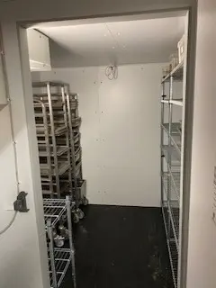 Værelse med to høje, hvide metalreoler og mange metalbøfler, der er sammenflettet og gemt. På gulvet er der flere hjulvogne,