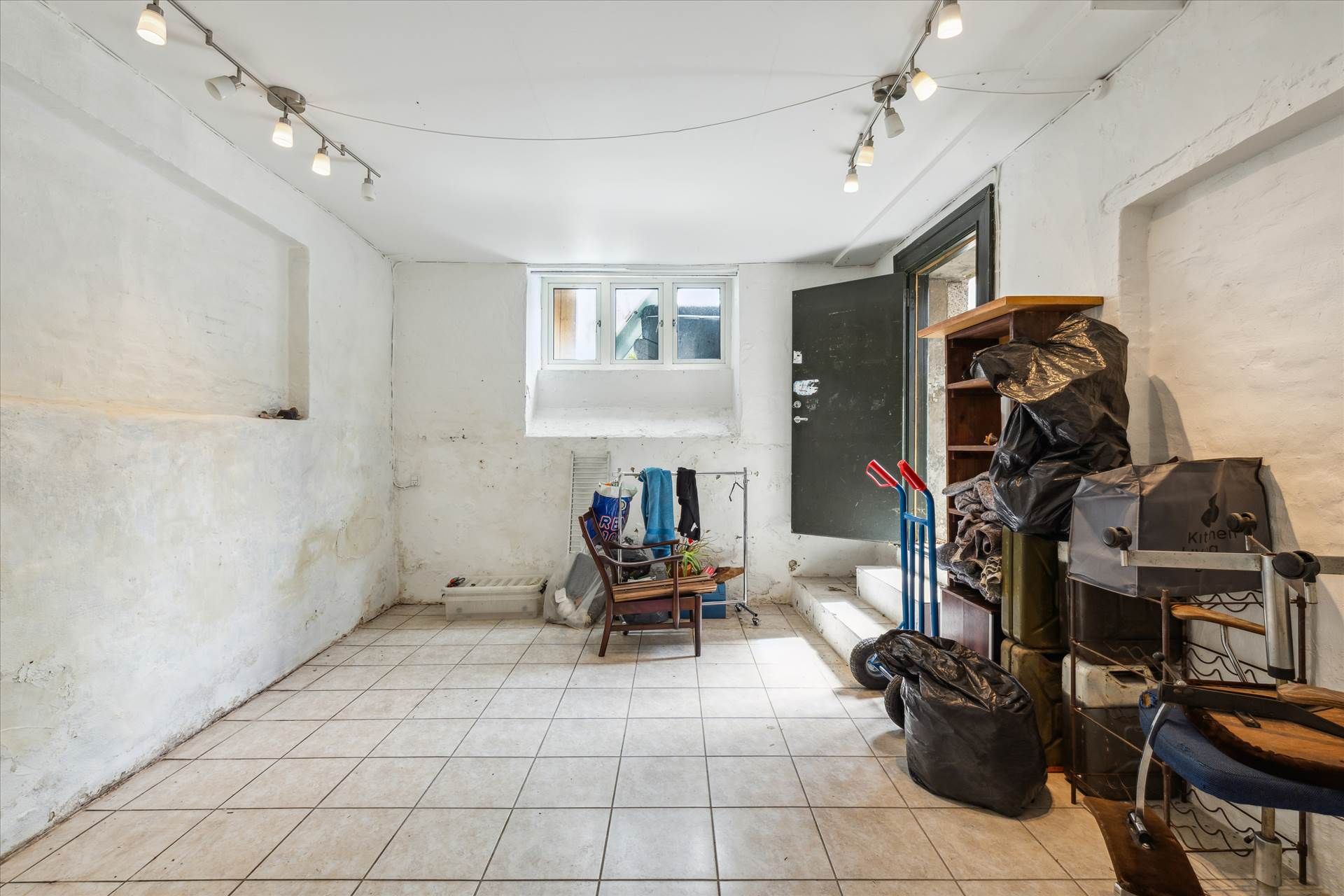 Ledig lagerlejemål med flere møbler og plastposer og kuffert samt rullekurv og lysekroner