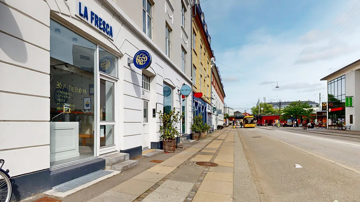 Vanløse bycenter med en gågade, butikker og en gåbro med planter og cykler langs vejen
