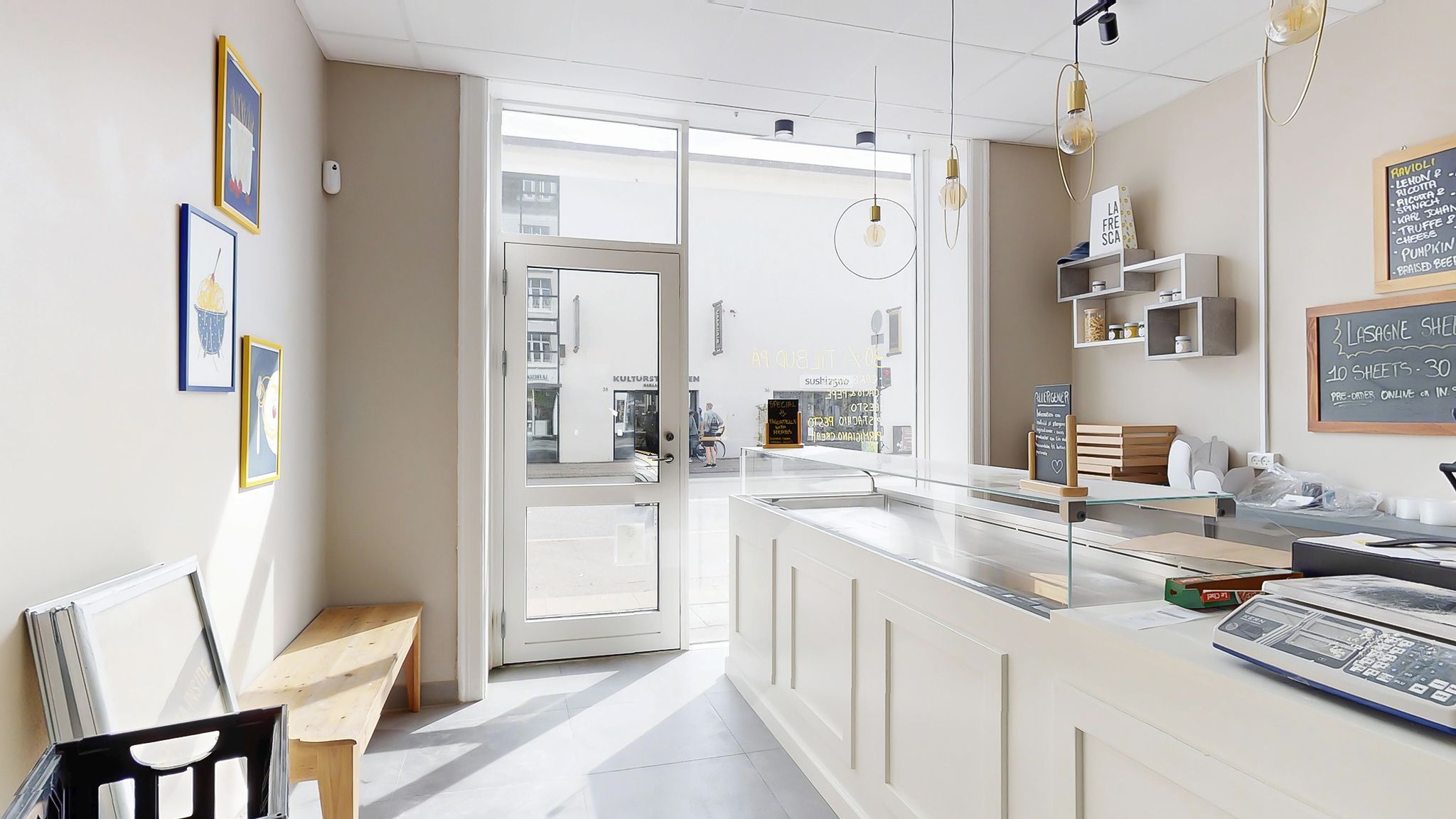 Et moderne butiksrum med hvidt panel og loft, slanke gulvlampe og lyse krydsfinergulve, der fremhæver en moderne indretning