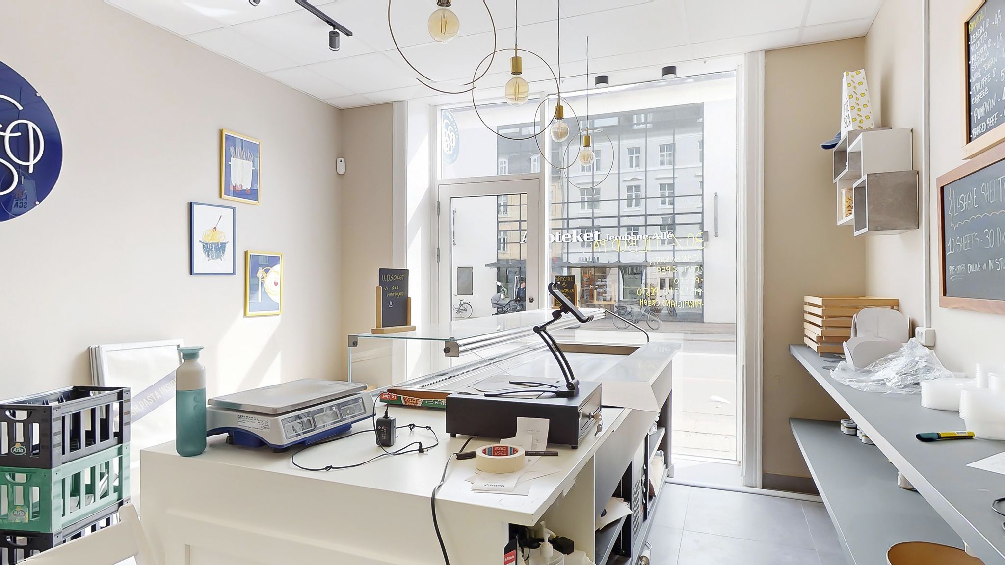 Køkken med vægte, skrivebord, lamper, lysekroner og udsigt til gaden i Vanløse